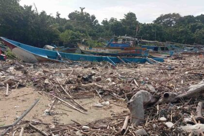Tumpukan sampah kiriman pascabanjir rob menutup jalur sandar perahu nelayan di Pantai Ujunggenteng, Kabupaten Sukabumi, Senin (2/2/2026). Kondisi ini menghambat aktivitas melaut warga pesisir. | Foto: Candra