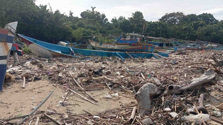 Tumpukan sampah kiriman pascabanjir rob menutup jalur sandar perahu nelayan di Pantai Ujunggenteng, Kabupaten Sukabumi, Senin (2/2/2026). Kondisi ini menghambat aktivitas melaut warga pesisir. | Foto: Candra