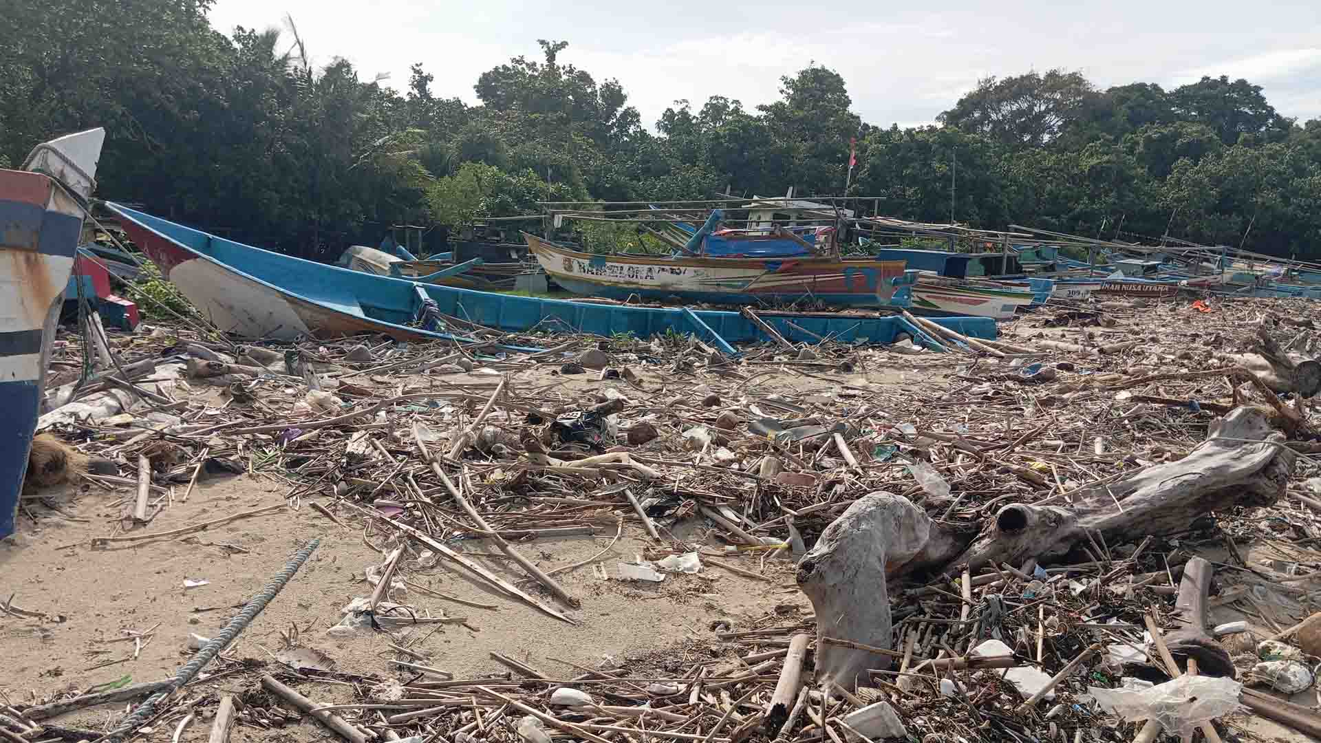 Tumpukan sampah kiriman pascabanjir rob menutup jalur sandar perahu nelayan di Pantai Ujunggenteng, Kabupaten Sukabumi, Senin (2/2/2026). Kondisi ini menghambat aktivitas melaut warga pesisir. | Foto: Candra